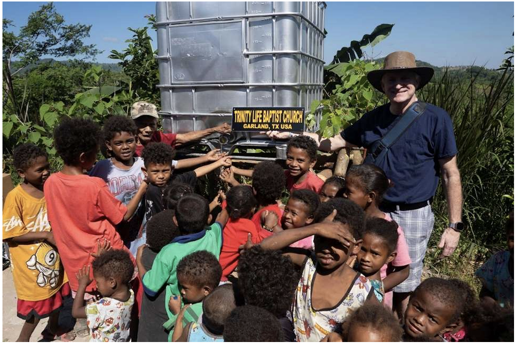 Donated water tank with community members